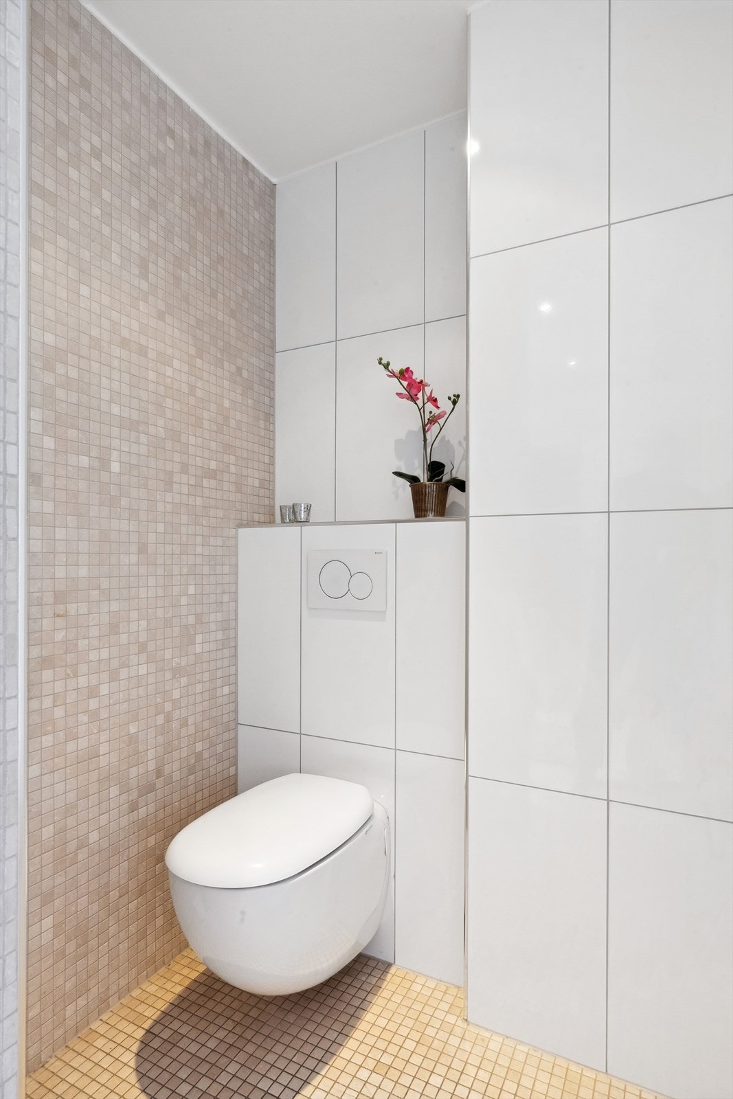 Bak servantinnredningen på motsatt side for dusjen er det vegghengt toalett. Galleribilde