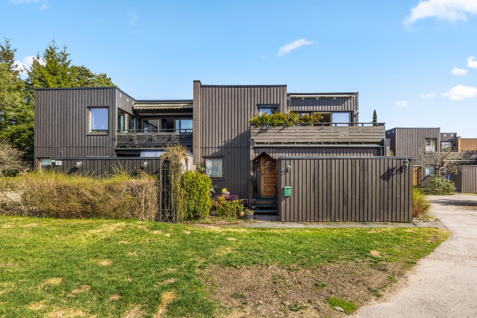 Fellestomten er pent opparbeidet med store plenarealer, asfalterte internveier, prydbusker og trær. Huset vender ut mot solrike friområder. Galleribilde