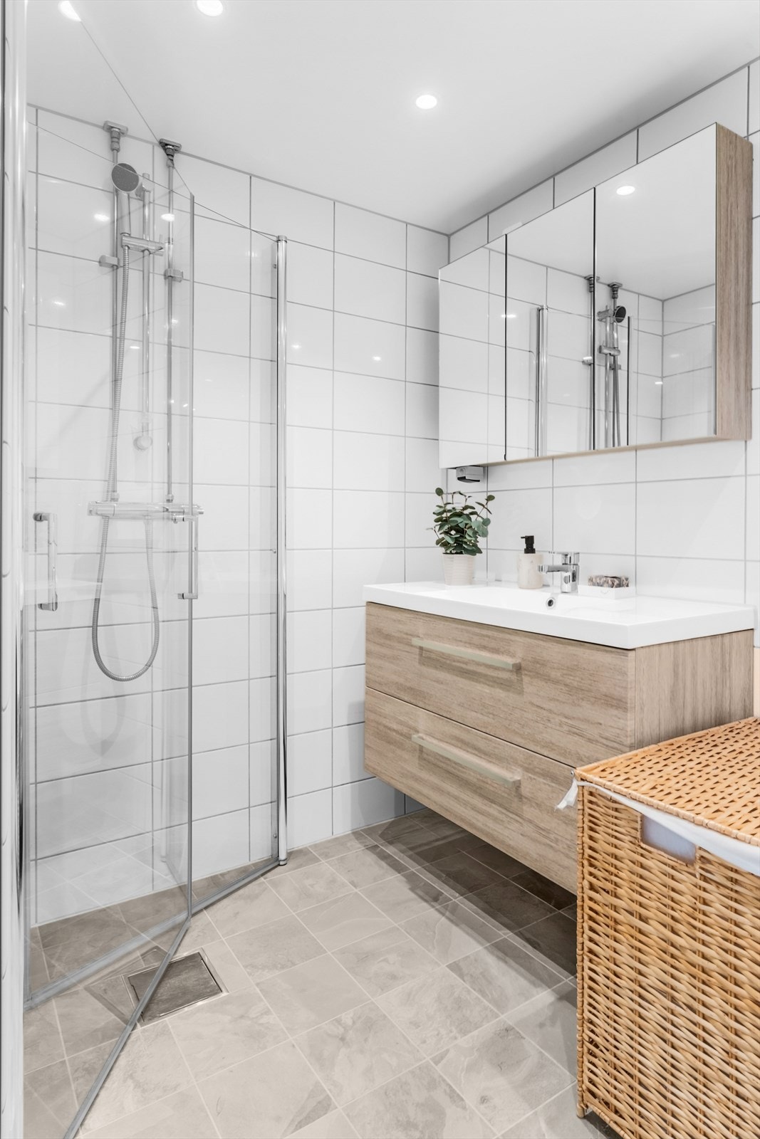 Badet er av god størrelse med flislagte vegger og malt himling med innfelte downlights. Innredning med servantinnredning, servant med ettgreps blandebatteri, speilskap, dusjdører, dusjarmatur, opplegg og plass til vaskemaskin. Galleribilde