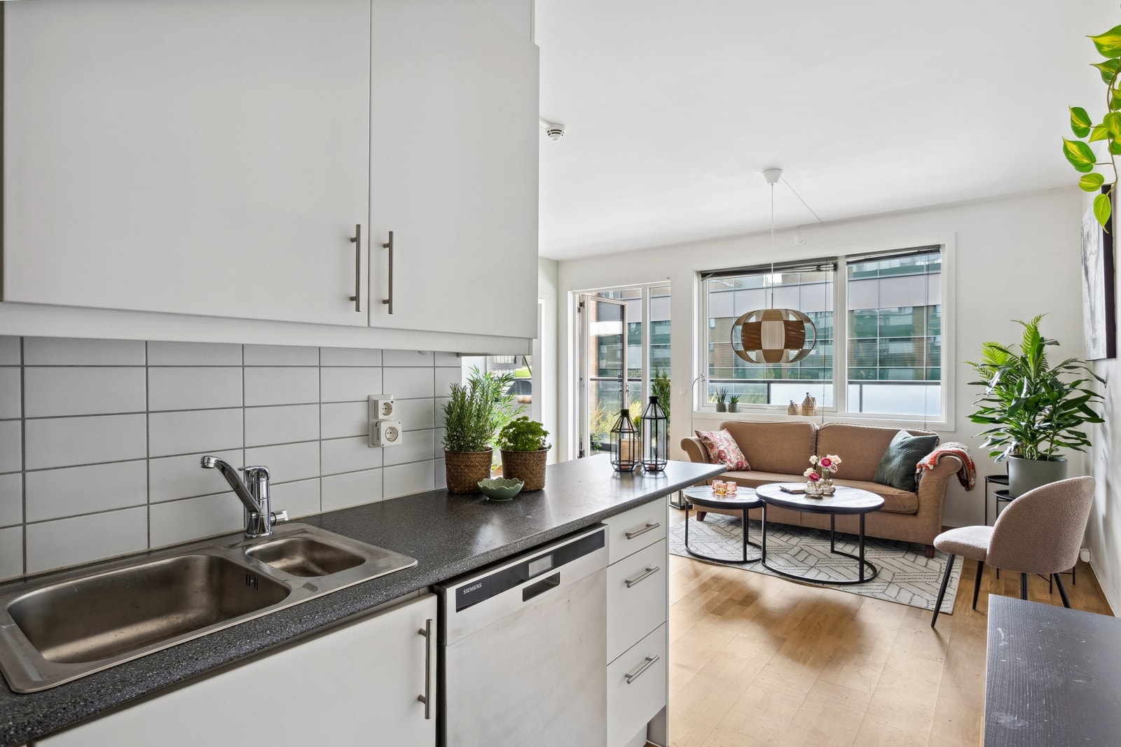 Lys kjøkkeninnredning med slette fronter, laminat benkeplate, ventilator og opplegg for oppvaskmaskin Galleribilde