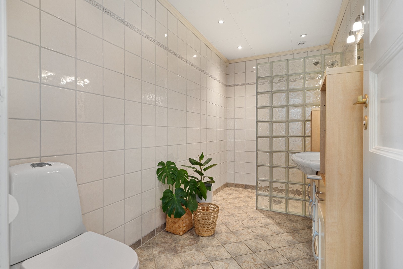 Badet har dusjnisje i glass, og spotter i himling. Galleribilde