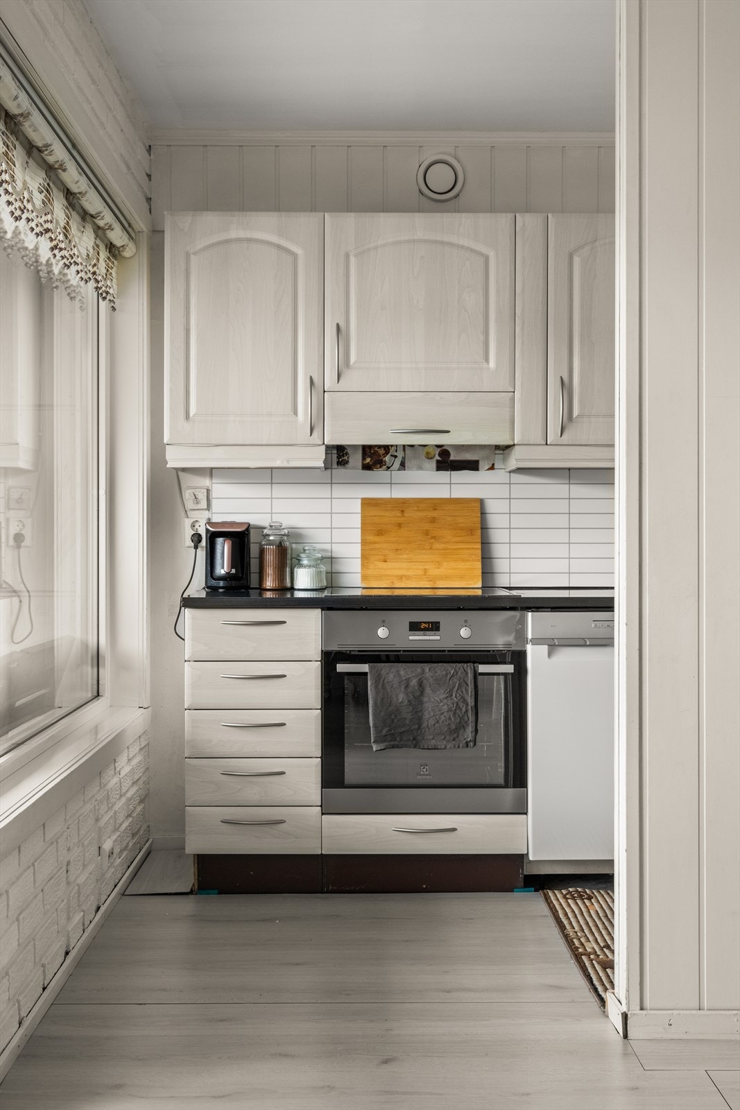 Kjøkkeninnredning fremstår med profilerte fronter. Laminert benkeplate med oppvaskkum og 1-greps blandebatteri, lys under overskap. Galleribilde