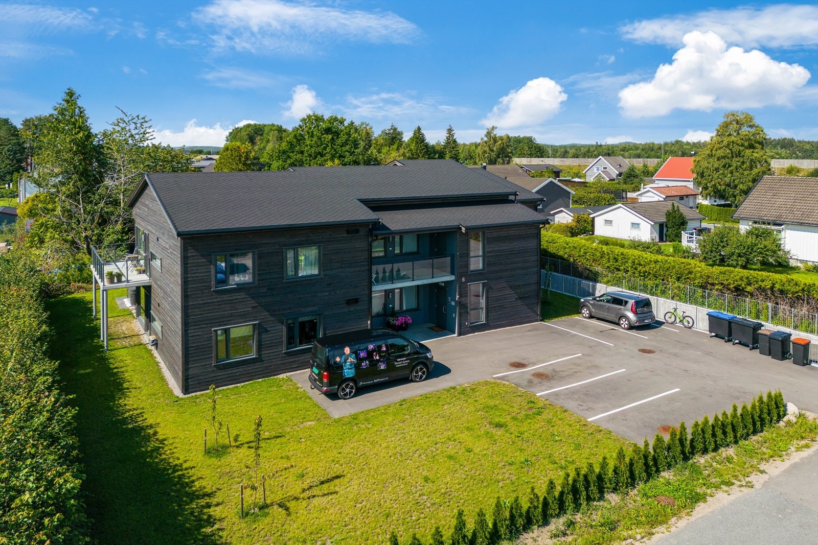 Flat tomt på 1333 kvm opparbeidet med biloppstillingsplasser på asfaltert grunn, plenarealer for felles benyttelse og prydbusker Galleribilde