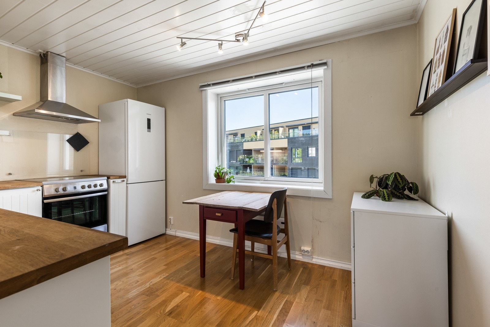 Innredningen har hvite, profilerte fronter, vitrinedører, takhøye skap og gyllen laminatbenkeplate med nedfelt kum i stål. Galleribilde