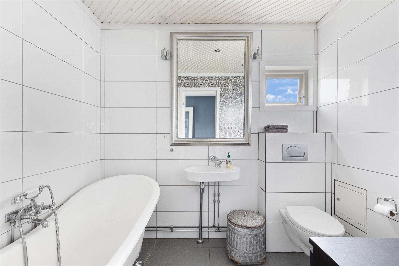 Badet i 2. etasje er flislagt med varmekabler. Innredet med badekar, vegghengt toalett og servant Galleribilde