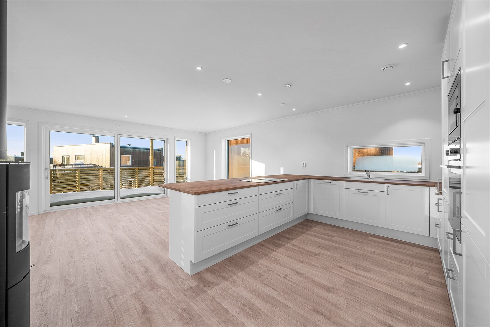 Stort og påkostet kjøkken med kjøkkenøy med barløsning og platetopp med innebygget ventilator Galleribilde