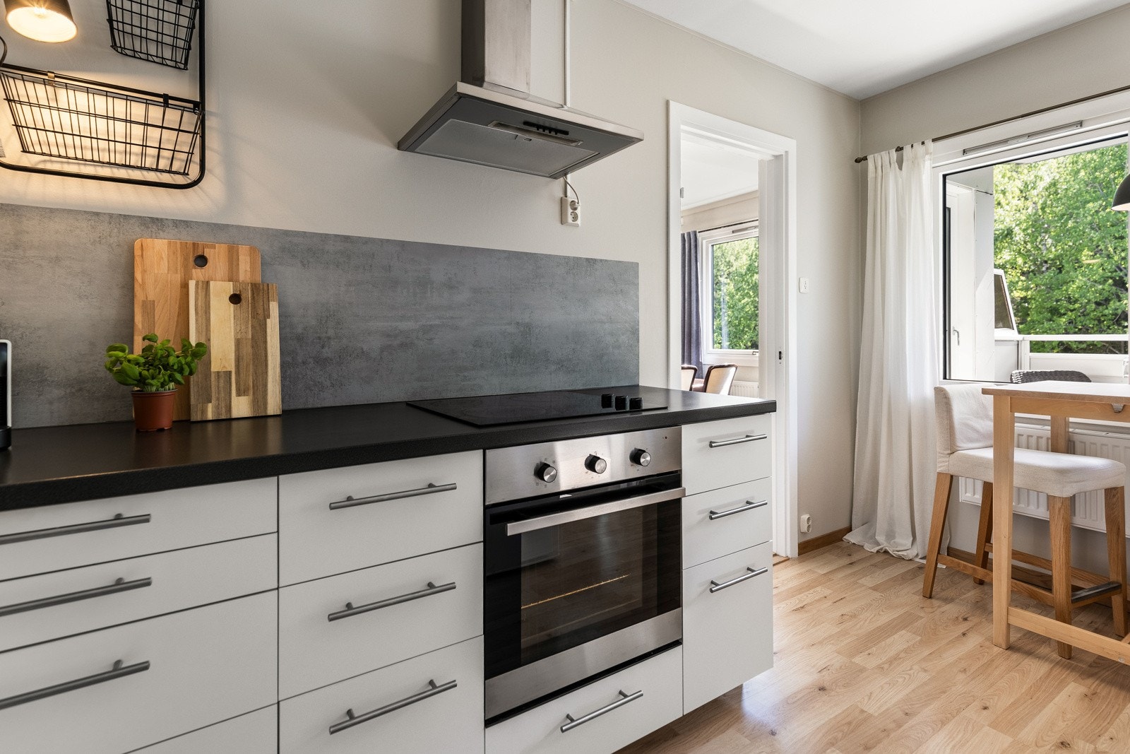 Innredningen har hvite, glatte fronter, benkebelysning, benkeplate i sort laminat og nedfelt oppvaskkum av metall. Galleribilde