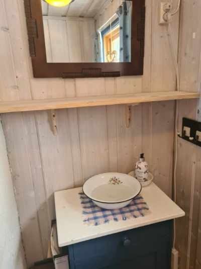 Hytta har et toalettrom med lakkerte tregulv, behandlet panel på veggene og et lite vindu som slipper inn lys. Galleribilde