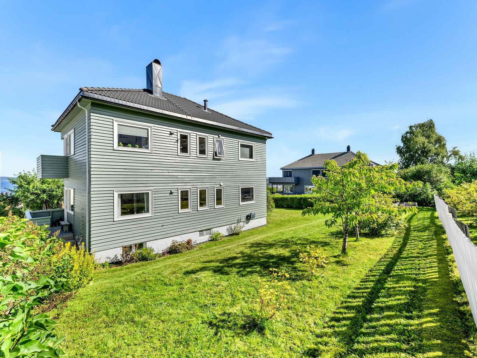 Tomten er pent opparbeidet og huset er omkranset av knallgrønn plen - og her er det etablert uteplasser hvor man nyter solen fra tidlig morgen til sen kveld på sommerstid. Galleribilde