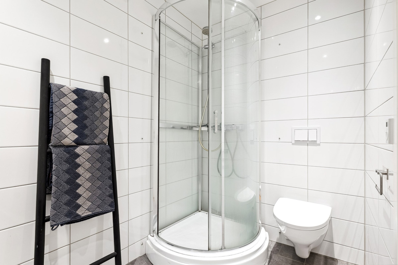 Badet er utstyrt med dusjkabinett og vegghengt toalett. Galleribilde