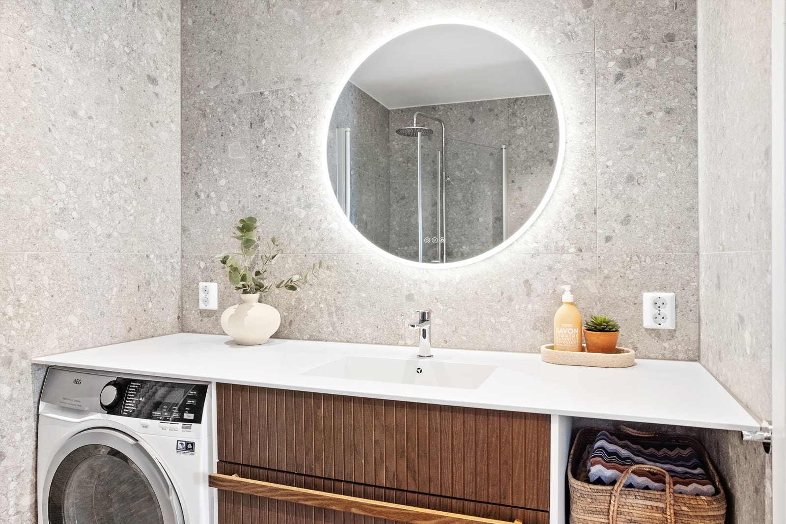 Badet er innredet med vegghengt toalett, servant med skap, speil med lys og dusjhjørne med svingbare glassdører. Det er opplegg for vaskemaskin og mekanisk avtrekk. Galleribilde