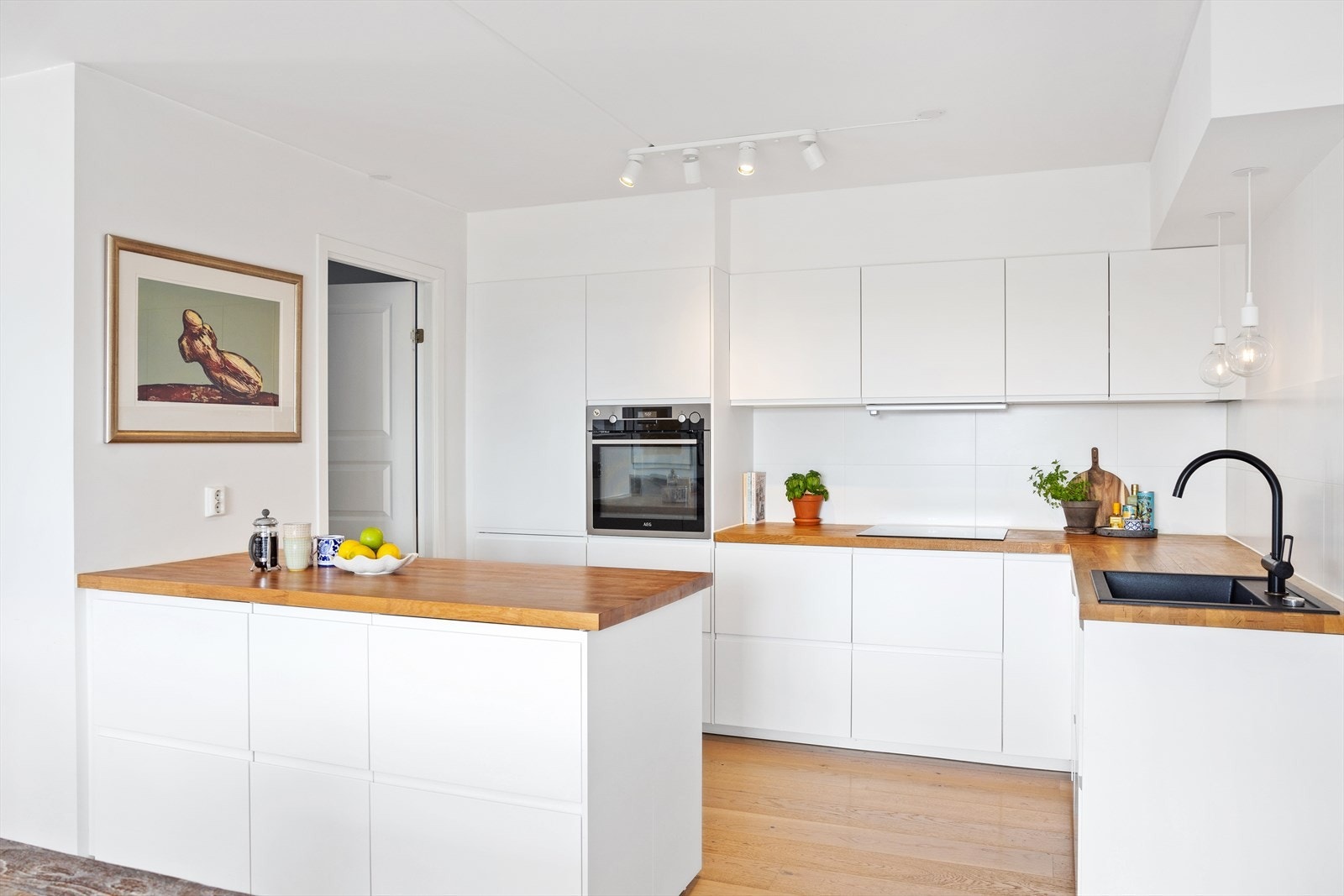 Kjøkkenet har glatte fronter, heltre benkeplate med nedfelt vaskekum, samt fliser og belysning over benkeplaten. Galleribilde