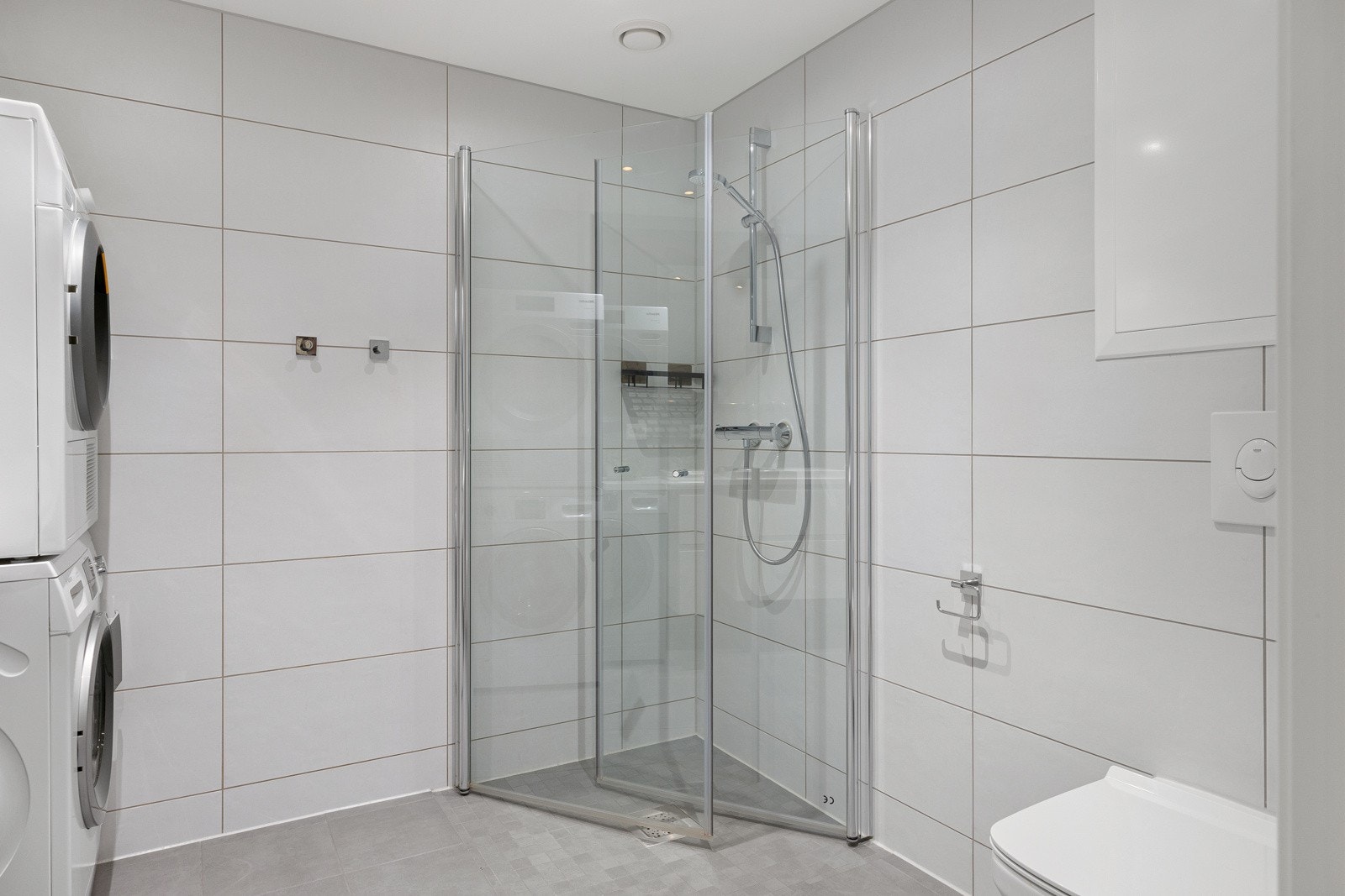 Innredning på det første badet består av servant, benkeskap med glatte fronter og laminat benkeplate, veggfestet toalett og dusj med innfellbare dører i herdet glass. Videre er det opplegg for vaskemaskin og plass til tørketrommel. Galleribilde