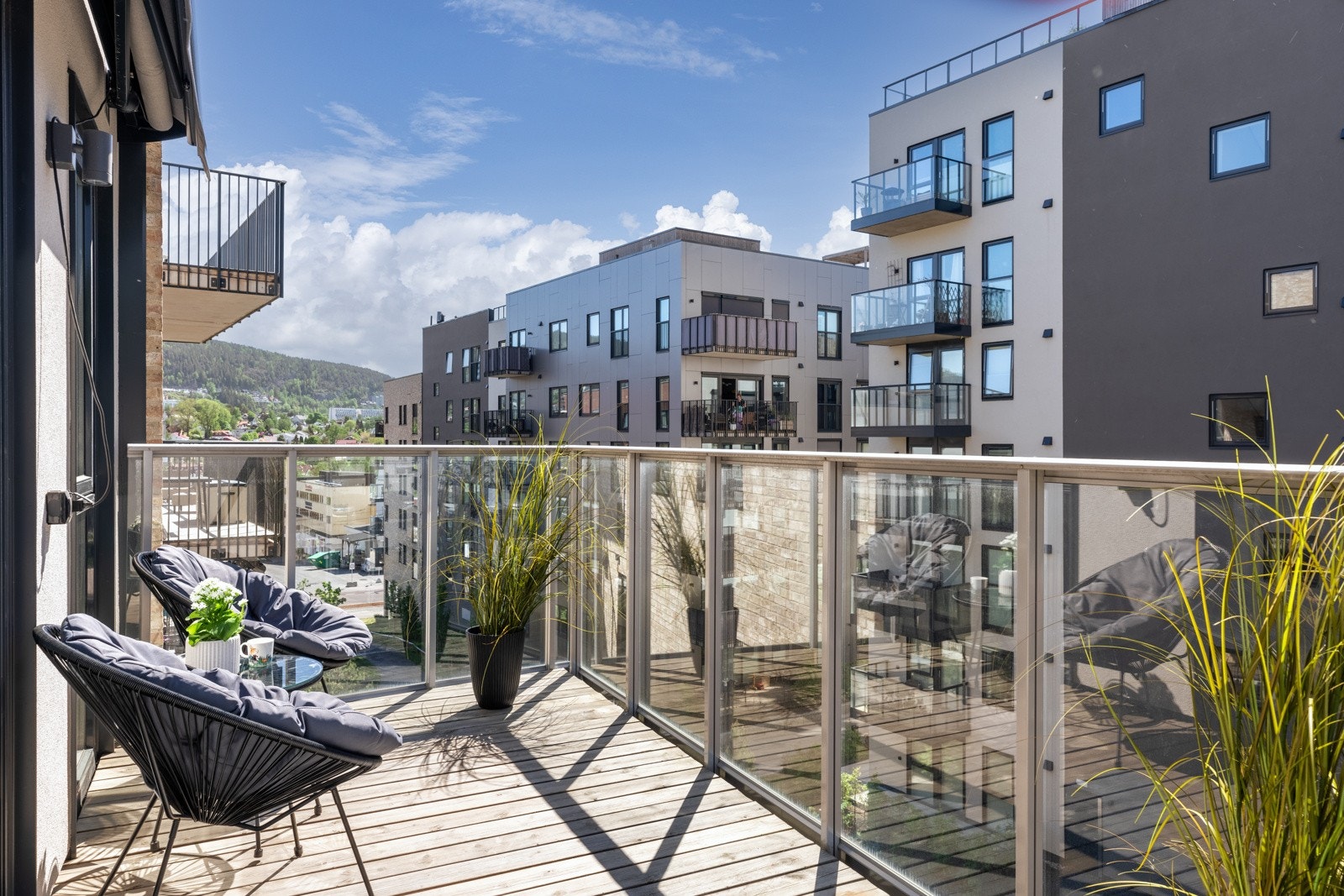 Sørvendt balkong på ca. 10 kvm med terrassebord på dekk og rekkverk i metall og glassplater. Galleribilde