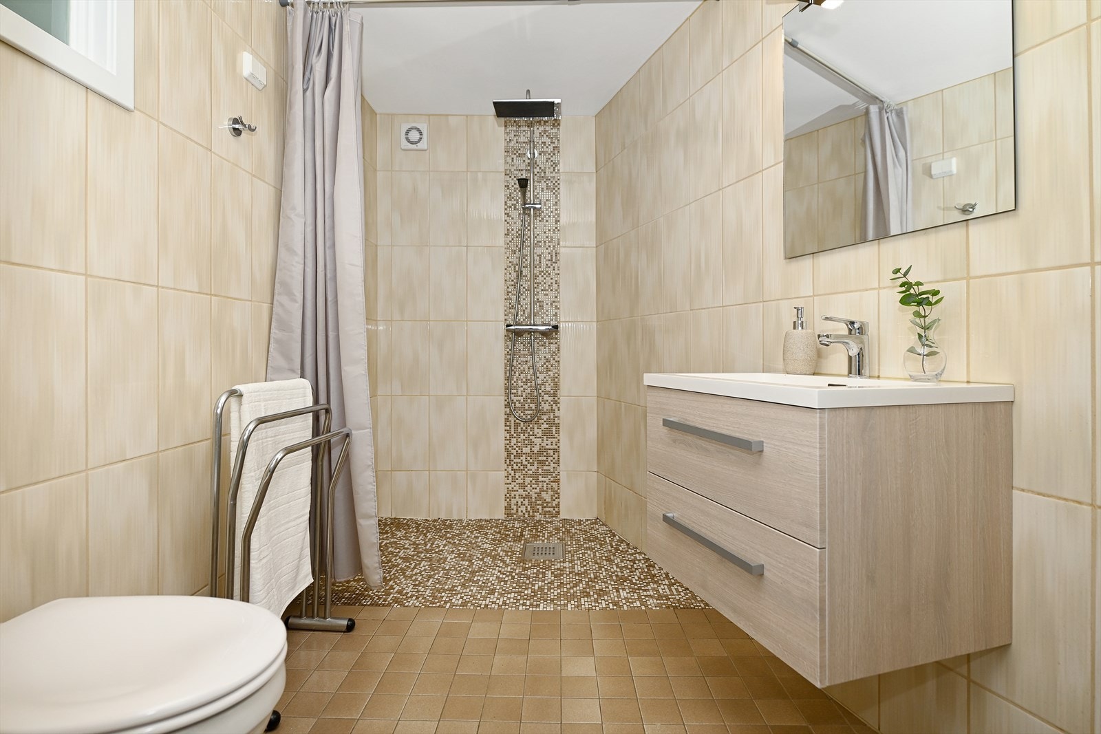 Badet er flislagt og har en moderne innredning og dusjnisje med takhøy dusj Galleribilde