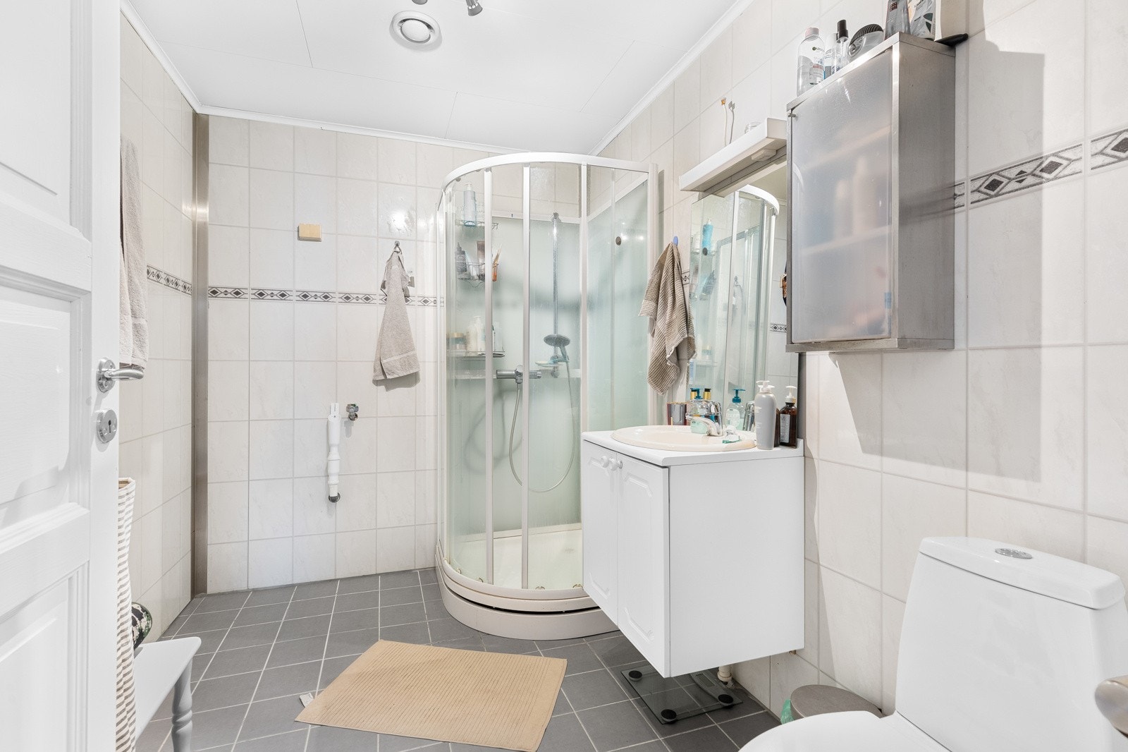 Badet har speil, overlys, baderomsinnredning med skapfronter, samt opplegg for vaskemaskin og tørketrommel. Galleribilde