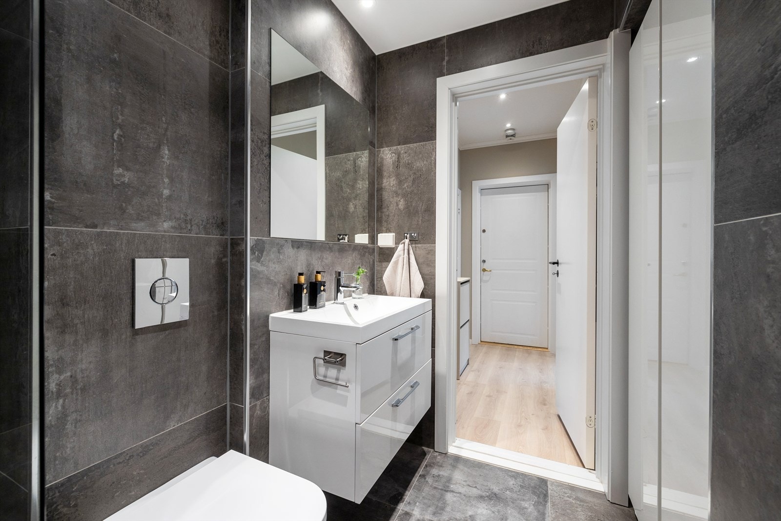 - Badet er innredet med nedfelt servant med underskap, veggmontert toalett og dusj med glassvegger - Galleribilde