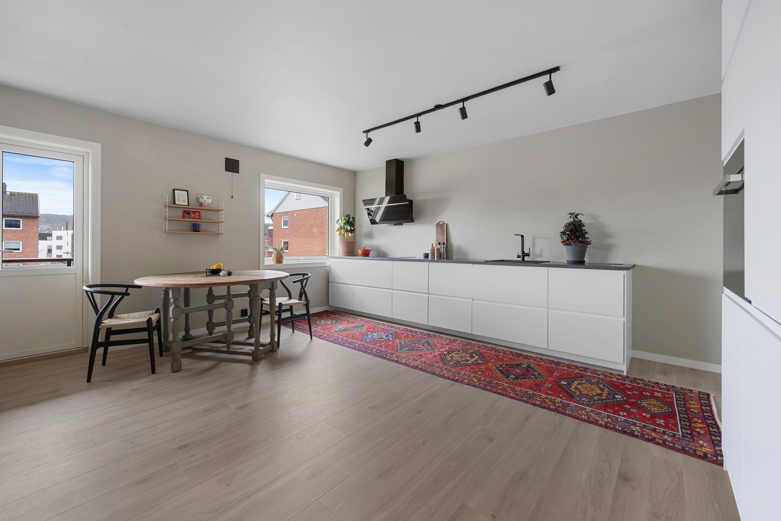 Kjøkkeninnredningen er fra IKEA, i moderne design med hvite, slette fronter og benkeplate i laminat med benkebeslag i kompositt Galleribilde