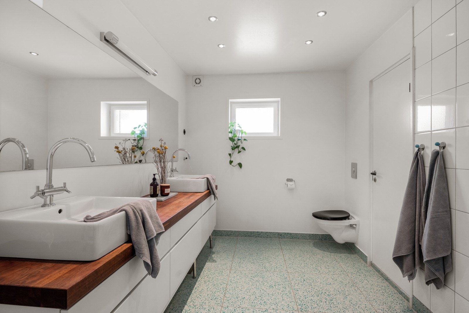 Videre er badet innredet med vegghengt toalett og innredning med to servanter og skuffer under. Galleribilde