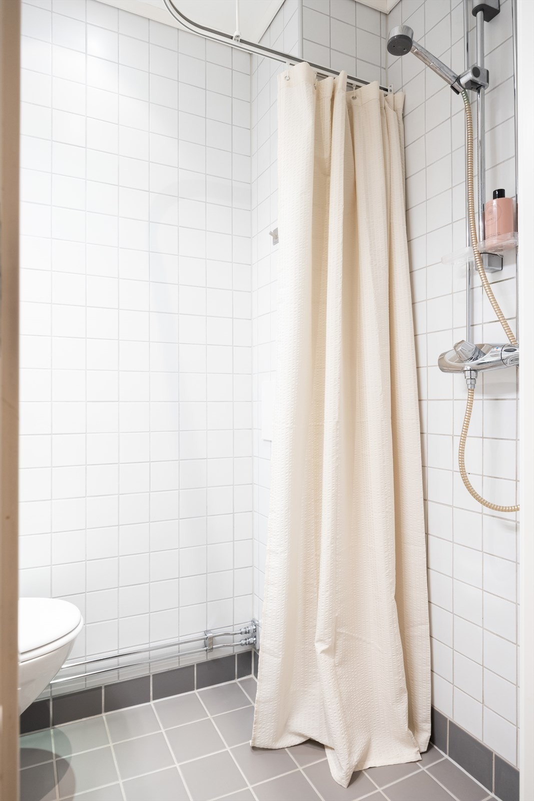 Badet er innredet med servant i skapseksjon, gulvmontert toalett og dusjhjørne Galleribilde