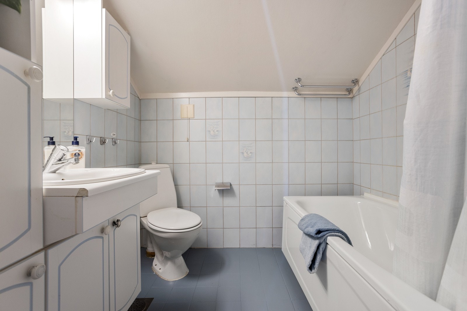 Badet i andre etasje har gulvvarme, toalett, badekar, nedfelt servant i en skapseksjon, et høyskap, veggskap og speil med belysning Galleribilde