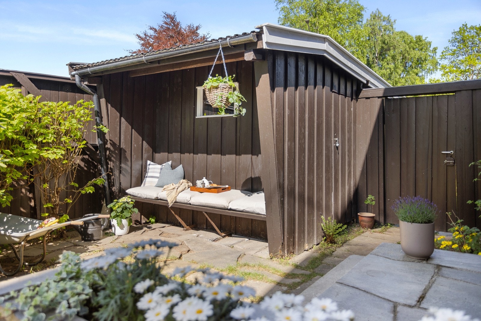 Det er en lun, plassbygd sittebenk på bakveggen til carporten Galleribilde