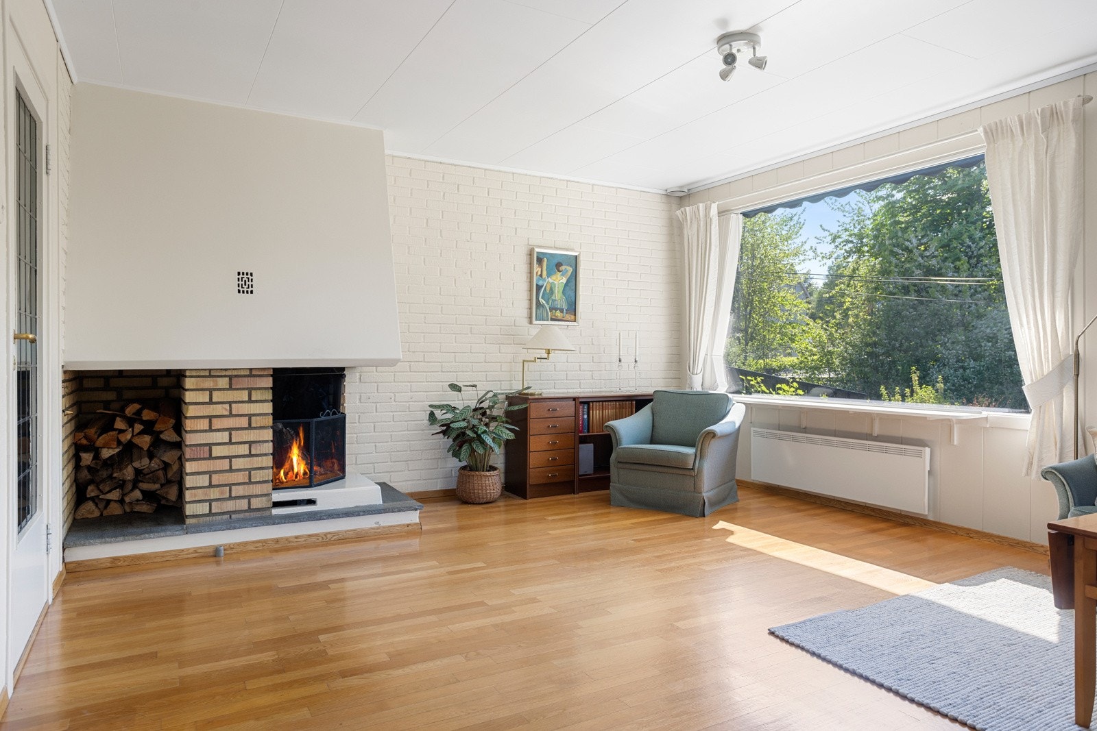 Det er god plass til sofagruppe, lenestoler og tv-/mediastasjon ved en åpen, oppmurt peis Galleribilde