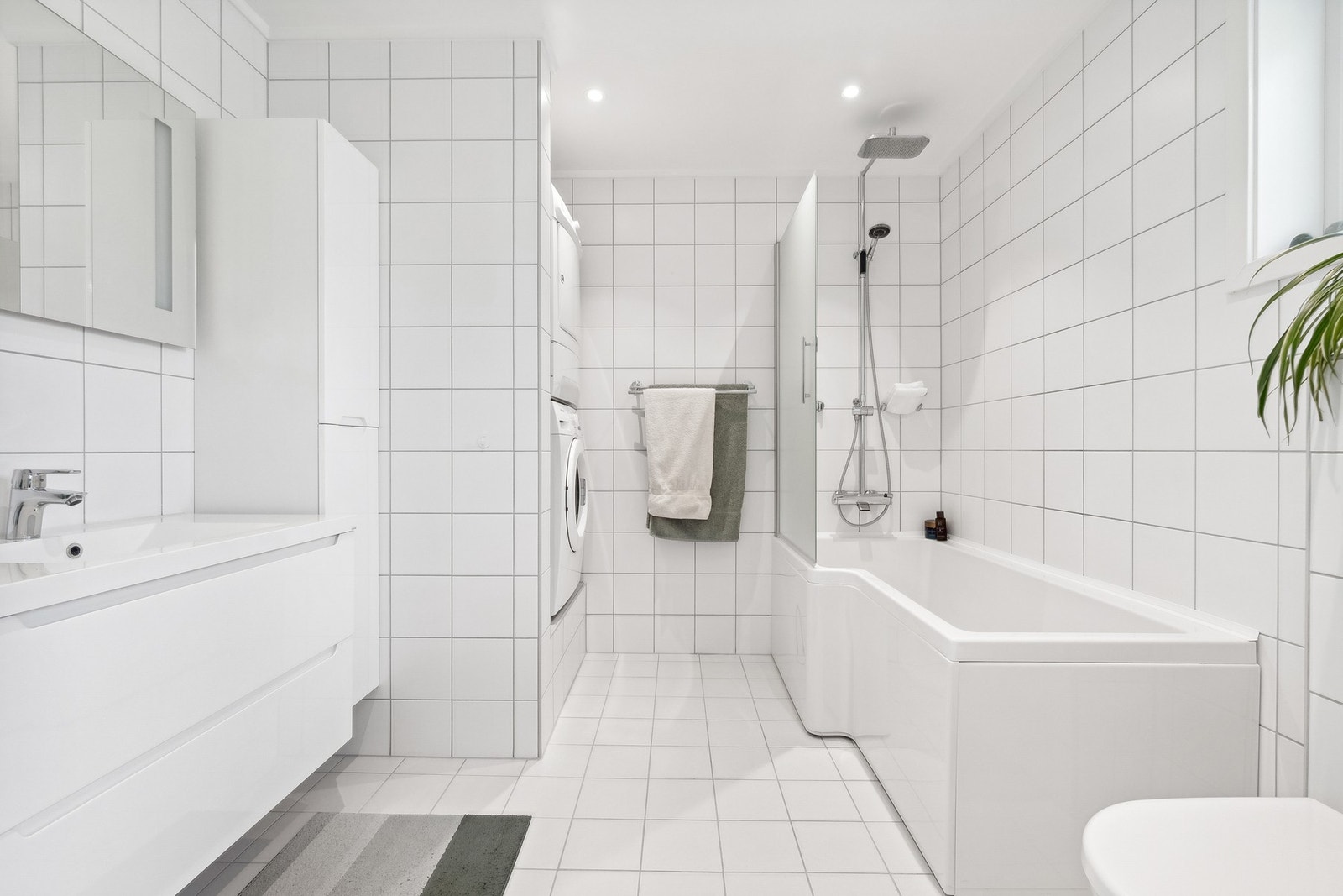 Lekkert bad med innredning, vegghengt wc, badekar, dusj på vegg, og opplegg for vaskemaskin. Galleribilde