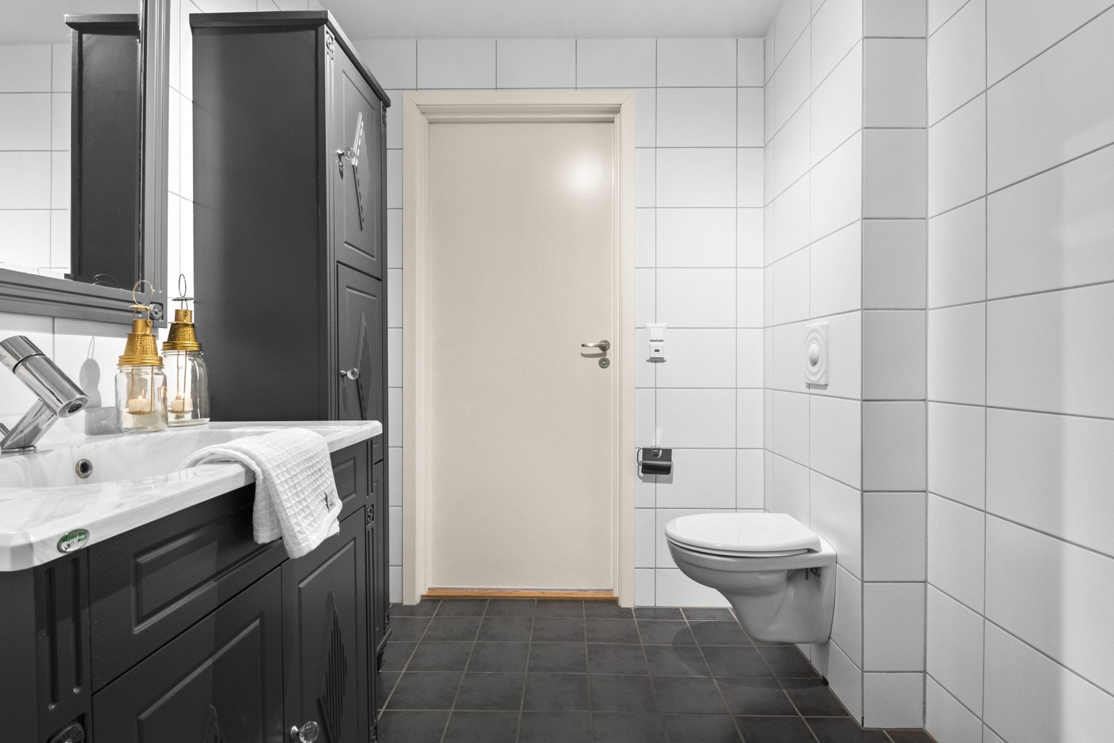 Flislagt baderom innredet med dusjnisje, servant med servantskap, høyskap og vegghengt klosett. Galleribilde