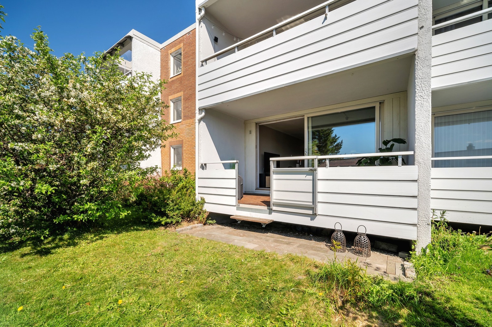 Trapp ned til steinbelagt markterrasse og solrikt grøntareal. Galleribilde