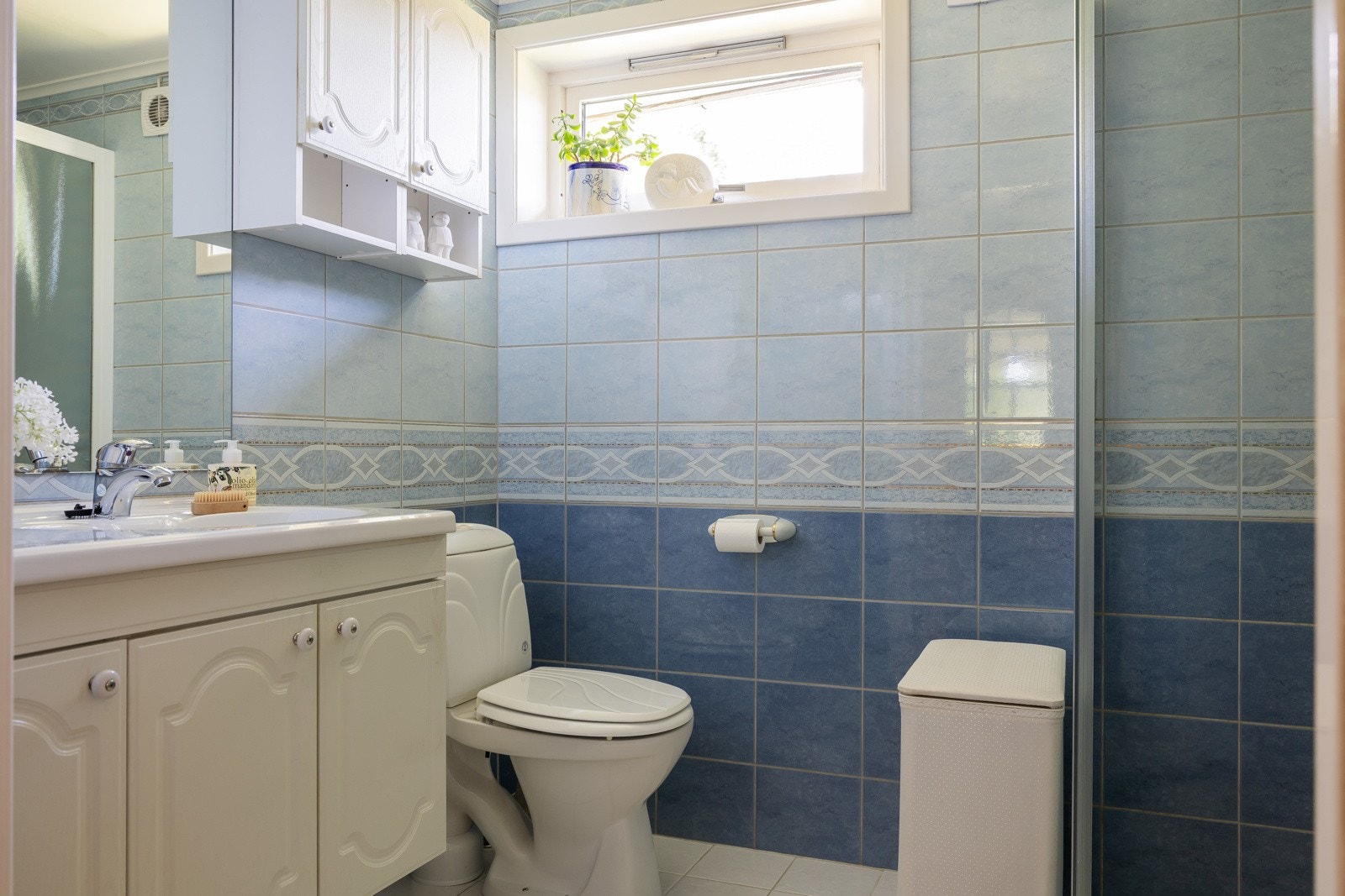 Badet har dusj med dusjvegger, gulvstående klosett, servant/baderomsinnredning og opplegg for vaskemaskin. Avtrekk med vifte i yttervegg. Galleribilde