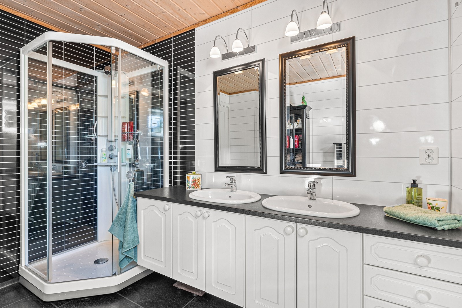 Baderomsinnredning med dobbel vask og et greps blandebatteri, dusjkabinett og vegghengt toalett. Galleribilde