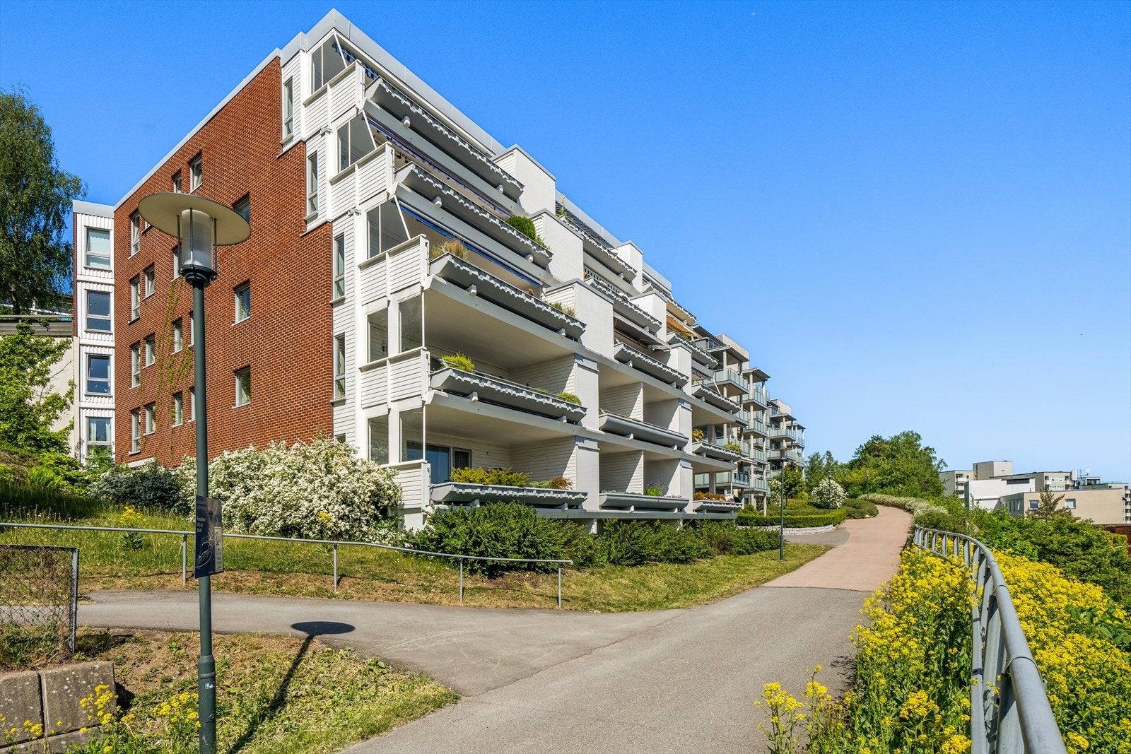 Pent opparbeidet fellestomt med asfaltert adkomst, plenarealer og beplantning - Sameiet har også lekeapparater og innendørs sykkelparkering Galleribilde