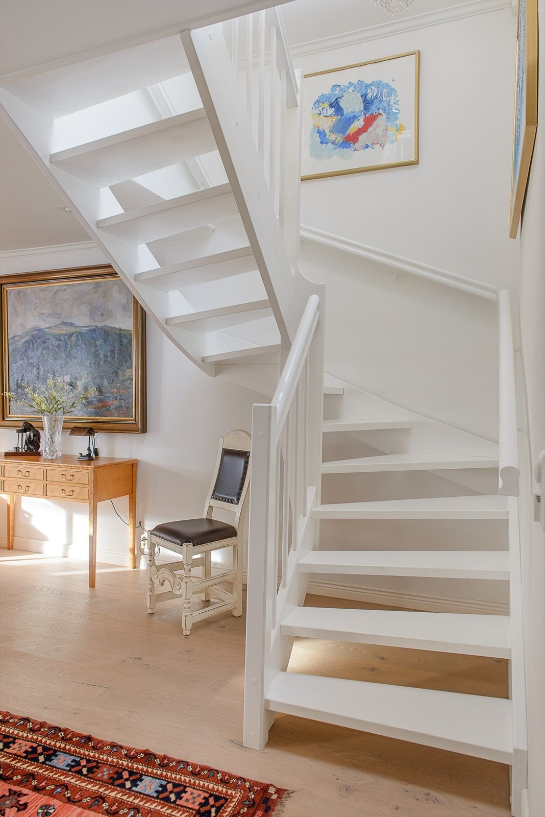 Forbindelsen mellom etasjene består av en hvitmalt tretrapp med åpne trinn. Galleribilde