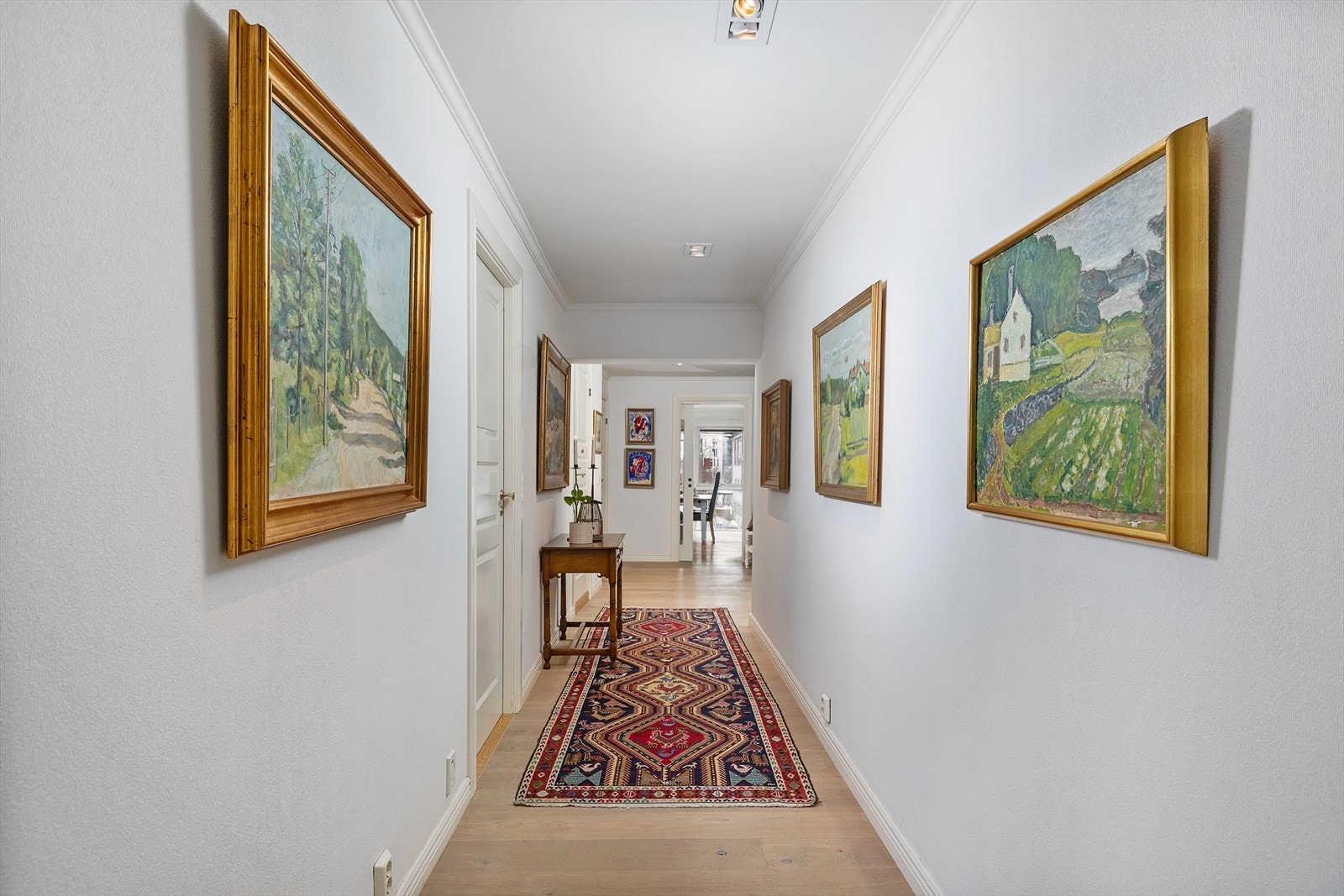Innbydende med lyse overflater og dowlights i himling i gangen inn mot kjøkkenet. Galleribilde