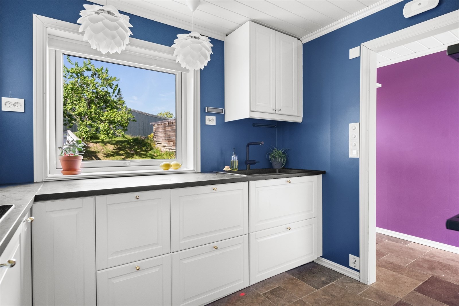 Fra kjøkkenet har du fint utsyn mot grøntarealer/plen ved inngangspartiet. Her kan du se barna leke mens du lager mat. Galleribilde