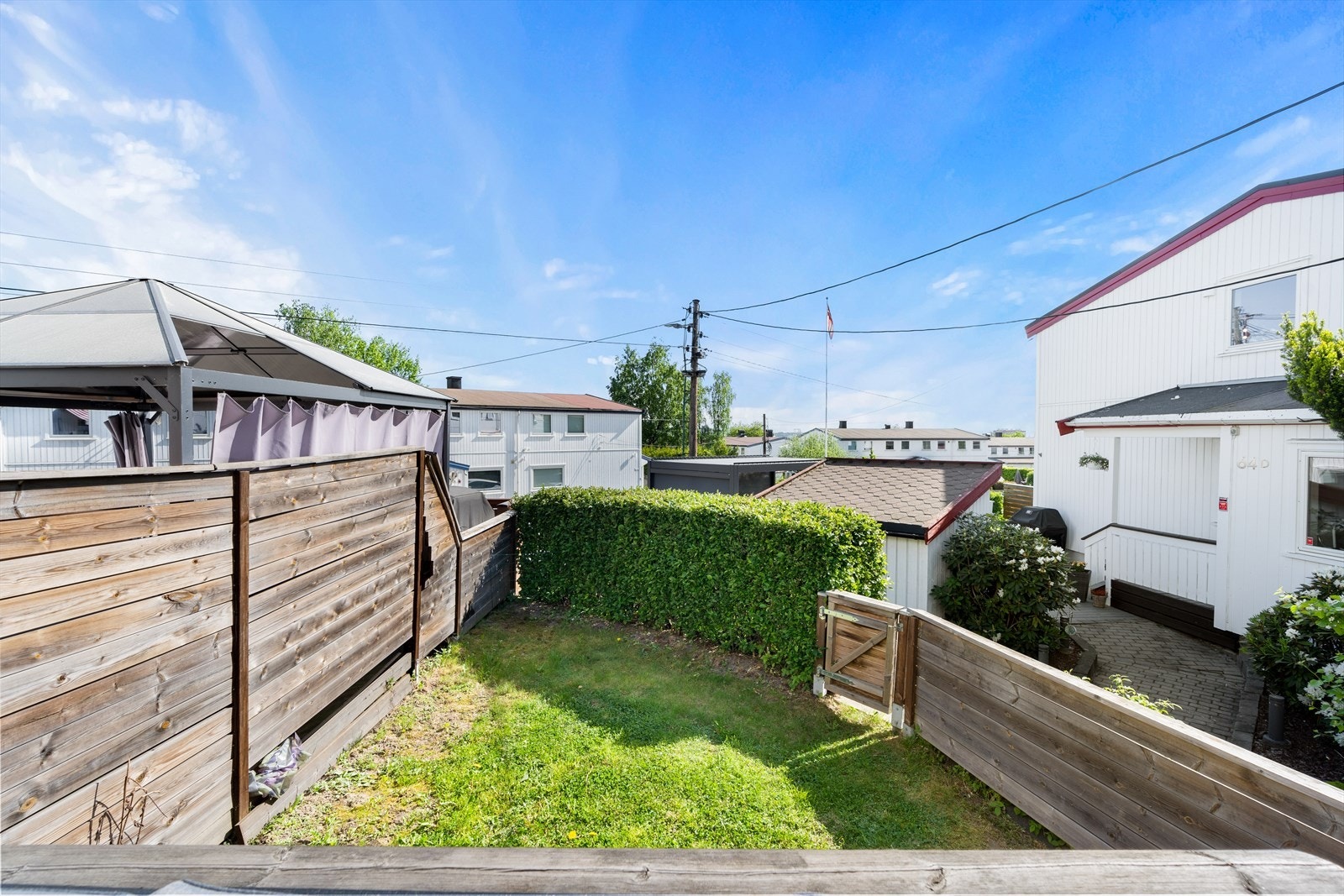 Hagen er inngjerdet i form av hekk, levegg, og det er port som går videre ned til veien. Galleribilde