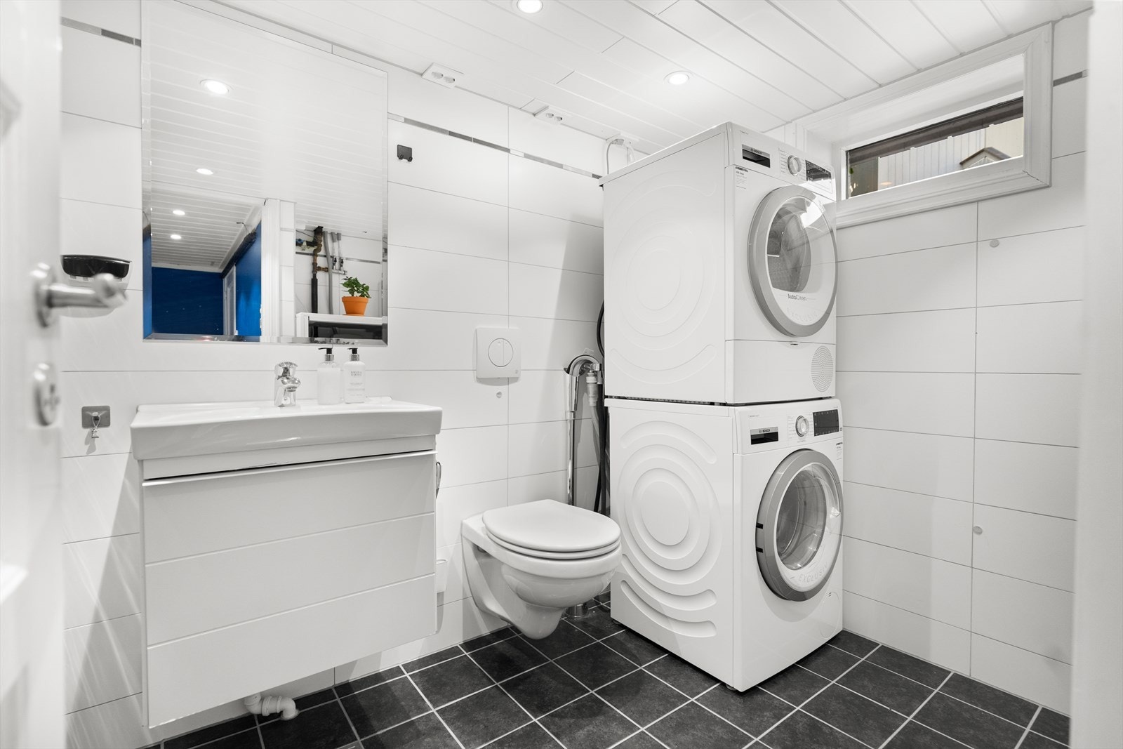 Badet i underetasje har opplegg for vaskemaskin/tørketrommel, vegghengt toalett, dusj og heldekkende servant. Galleribilde