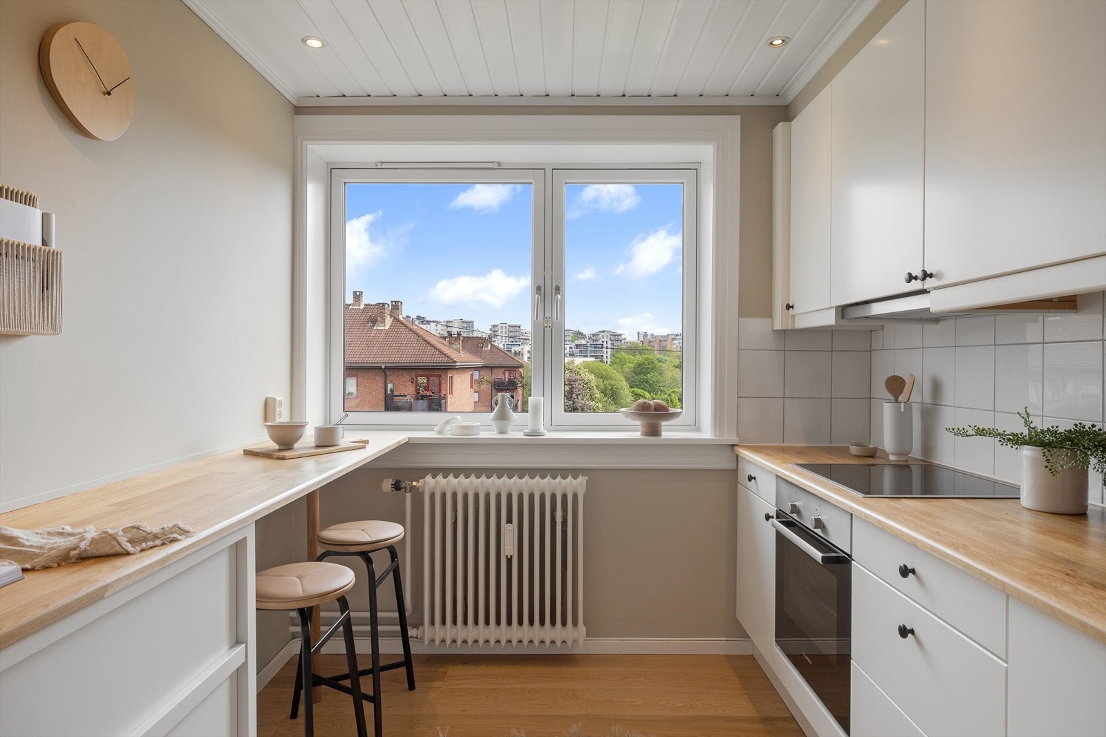 Kjøkkenet inneholder innredning med glatte fronter, heltre benkeplate, oppvaskkum, ventilator, fliser over benk og opplegg til oppvaskmaskin. Galleribilde