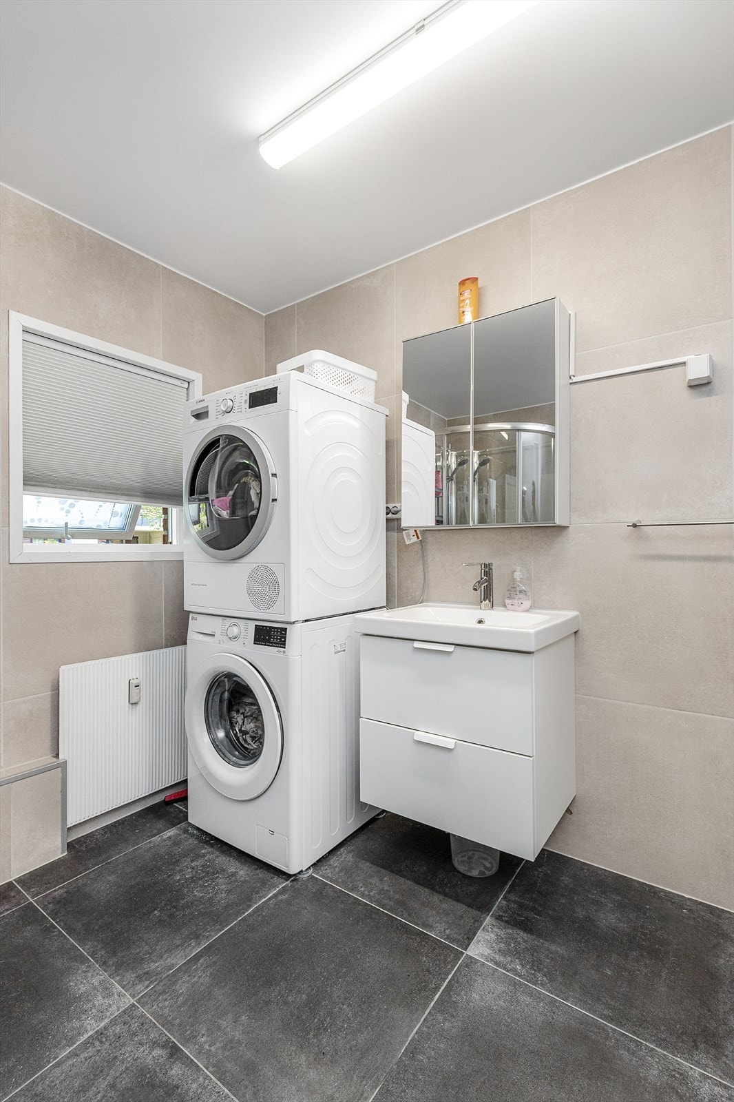 Videre har badet både plass og opplegg for vaskemaskin og tørketrommel. Galleribilde