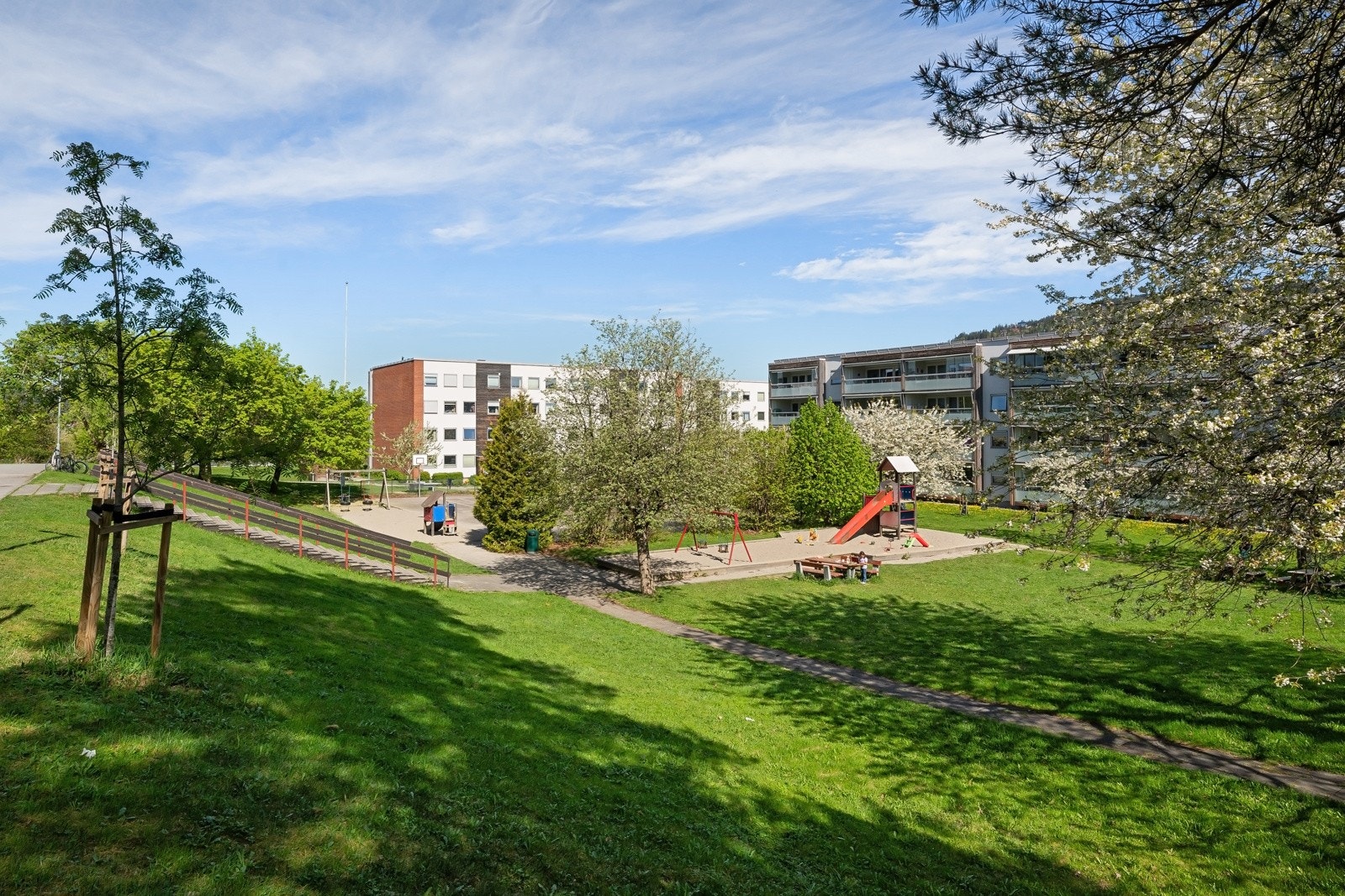 Opparbeidede fellesarealer med plener, prydbusker, tuntrær, lekeapparater, asfalterte adkomstveier og gangveier. Galleribilde