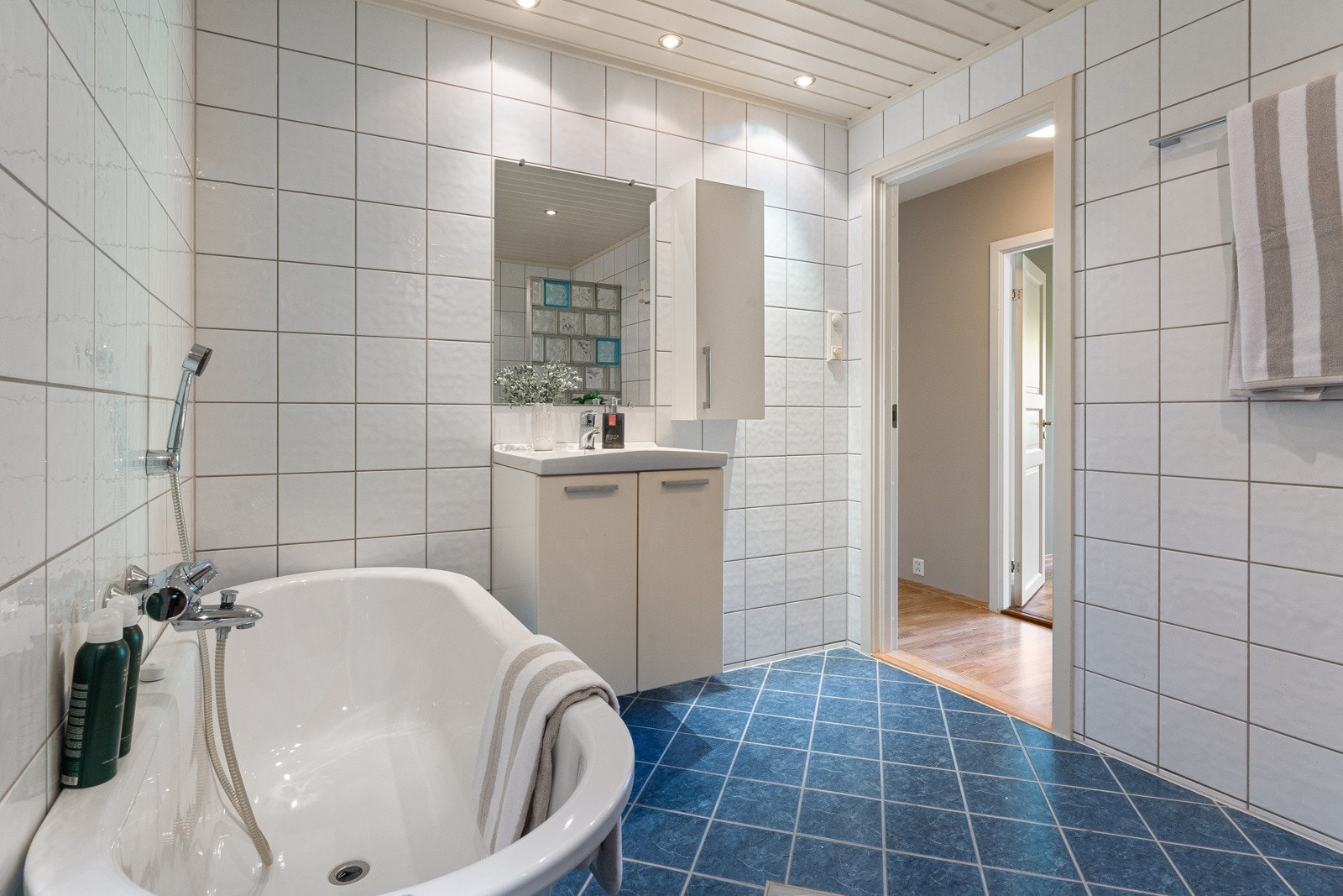 Innredet med nedfelt servant, veggmontert toalett, badekar og dusjhjørne. Galleribilde