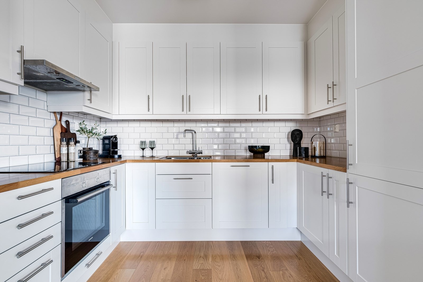 Lyst og delikat kjøkken med profilerte fronter og fliser på bakvegg. Her har du rikelig med skap- og benkeplass å boltre deg på! Galleribilde