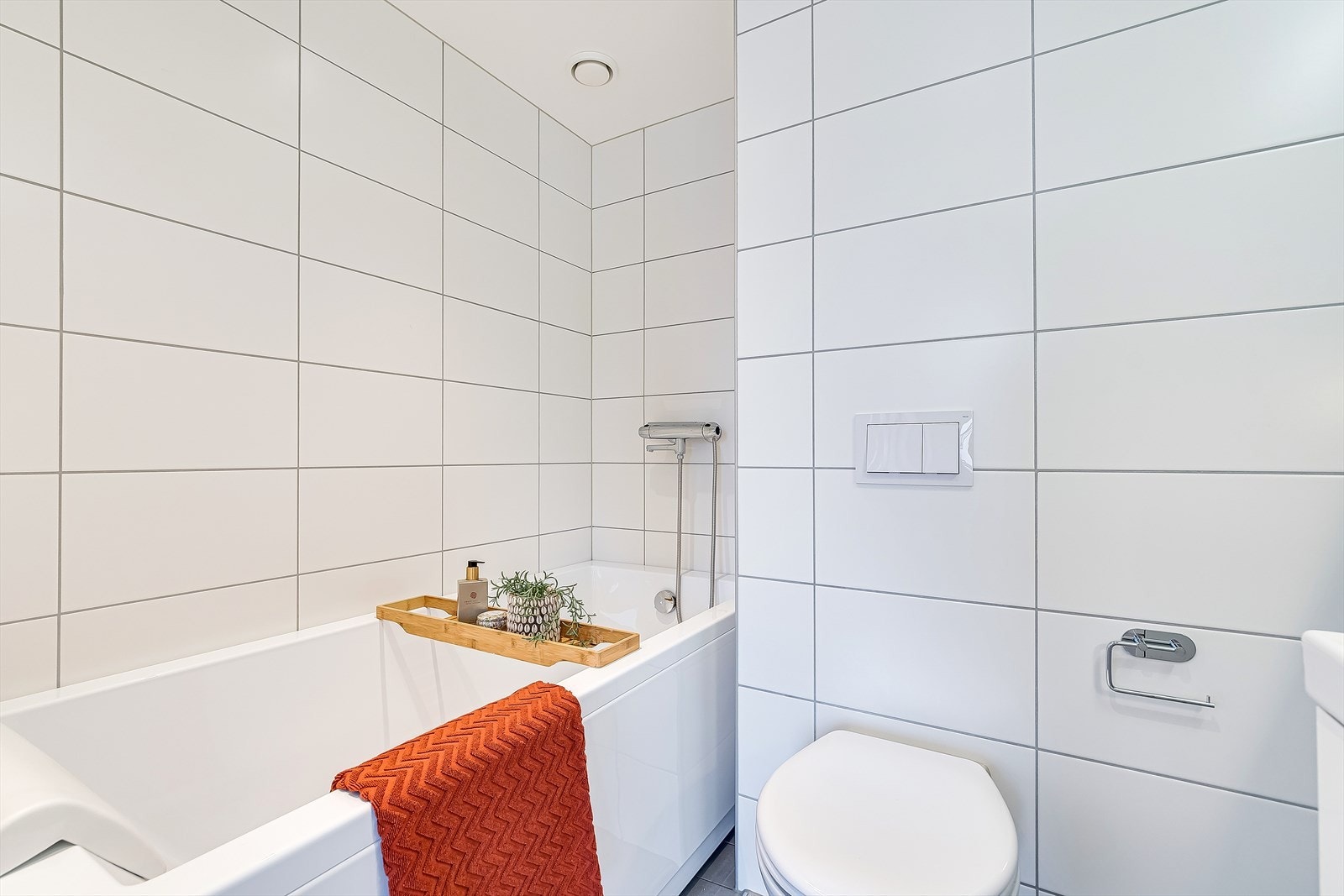 Bad II er flislagt med lyse fliser og har varmekabler i gulv. I hjørnet finner du et flott badekar - den perfekte avslappning etter en lang dag. Galleribilde