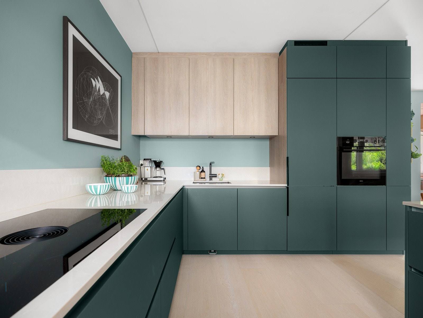 Benkeplaten er forlenget delvis opp mot bakveggen, som sikrer en sømløs overgang og enklere rengjøring. Kjøkkenet har blandebatteri med uttrekkbart munnstykke og underlimt vask i antrasitt-utførelse, begge fra Blanco. Galleribilde