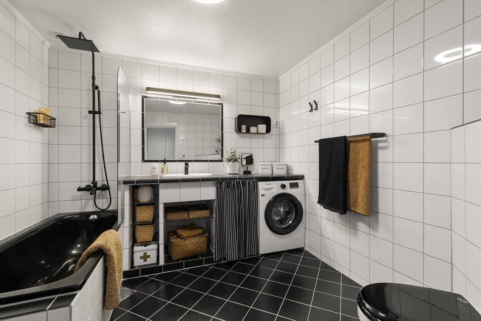 Badet har innredning med nedfelt servant, veggmontert toalett, badekar, dusjvegger/hjørne og opplegg for vaskemaskin. Galleribilde