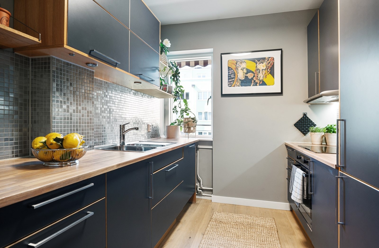 Kjøkkeninnredning fra Marbodal med glatte mørkegrå fronter med eikebelistning og benkeplate av eik med nedfelt vaskekum og induksjon platetopp. Galleribilde