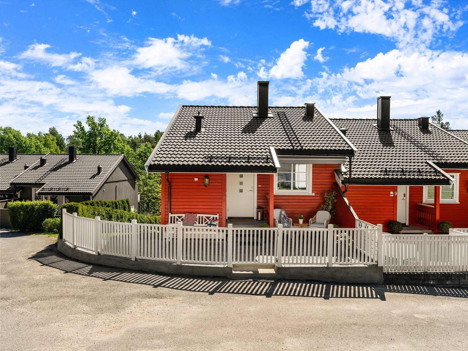 Hvitmalt stakittgjerde rammer inn gårdsplassen. Galleribilde