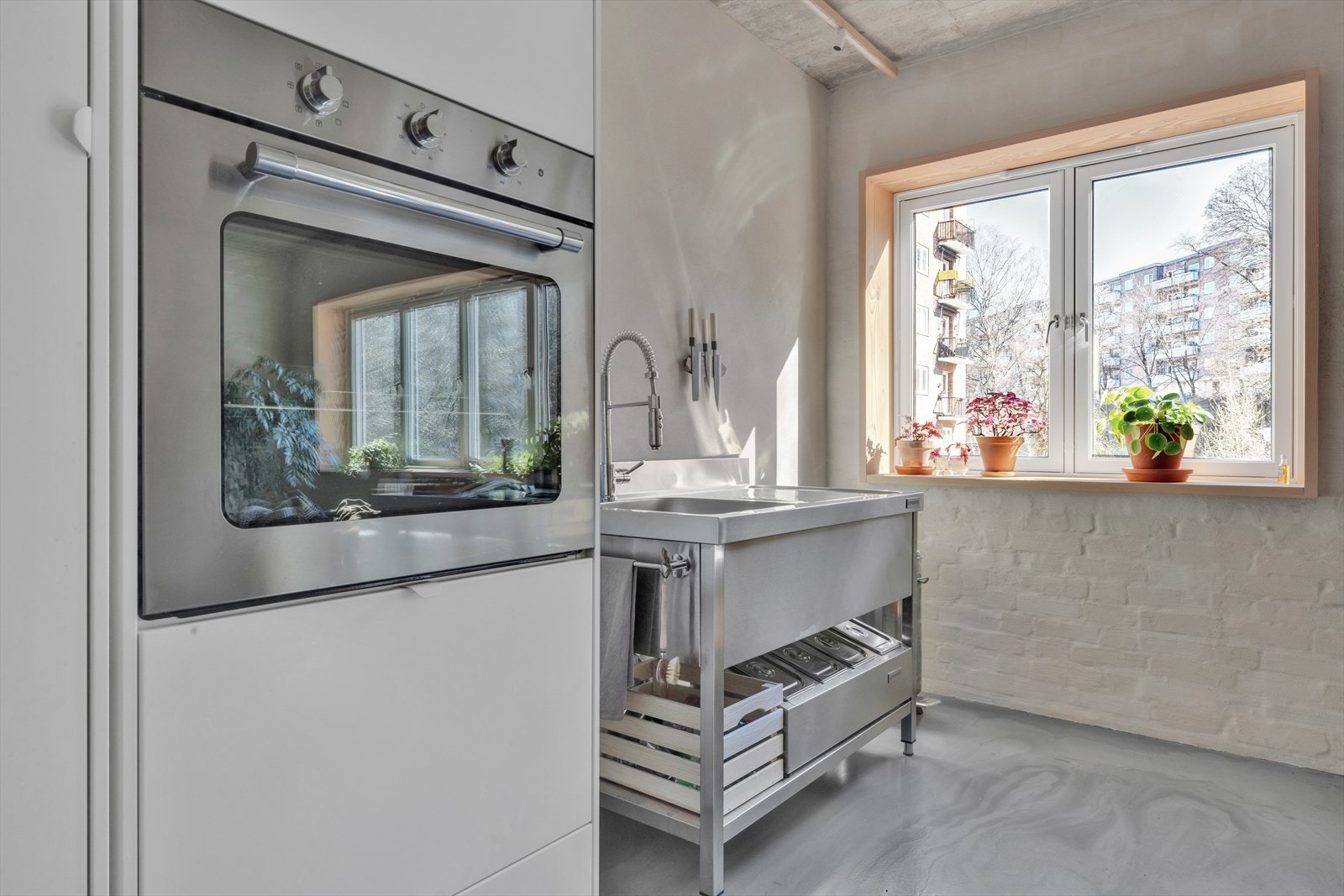 Kjøkkeninnredning fra 2023/24 bestående av hvite slette fronter samt integrerte hvitevarer som kjølskap/fryser og ovn Galleribilde