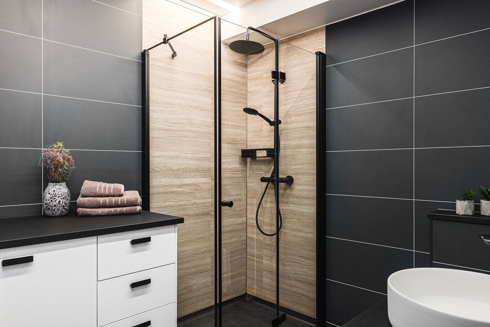 Nyere bad fra 2020 med tøffe kontraster som skaper en lun atmosfære. Badet har en moderne innredning og godt med skapplass. Dushjørne med innfellbare dusjdører og veggmontert dusjbatteri. Galleribilde
